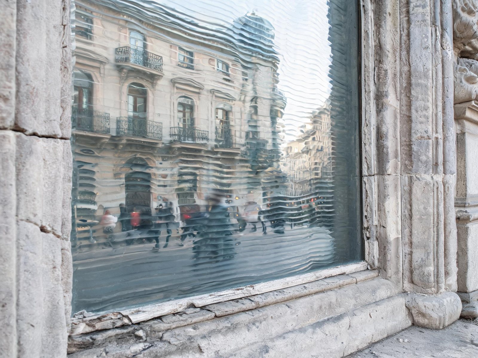 Détail d'un vitrage en verre étiré ancien avec ondulations caractéristiques visible en lumière rasante